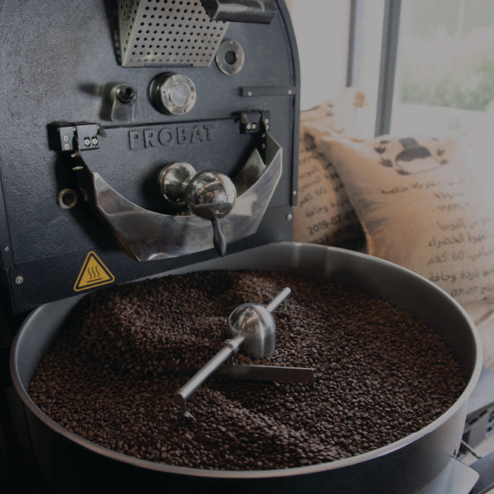 Probat Coffee roastery with roasted coffee beans on it and green beans sack next to it