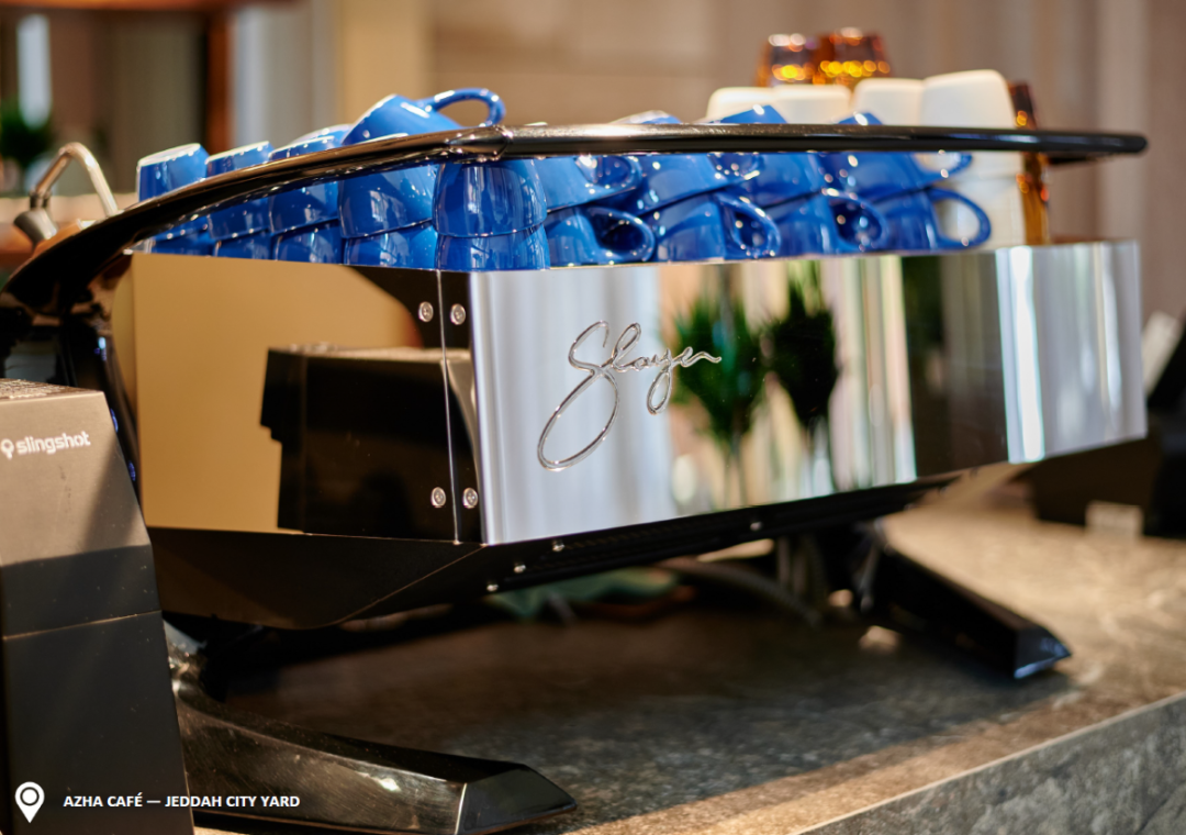 Metalic Slayer Coffee Machine on a rocky bar. and blue coffee mug above the machine